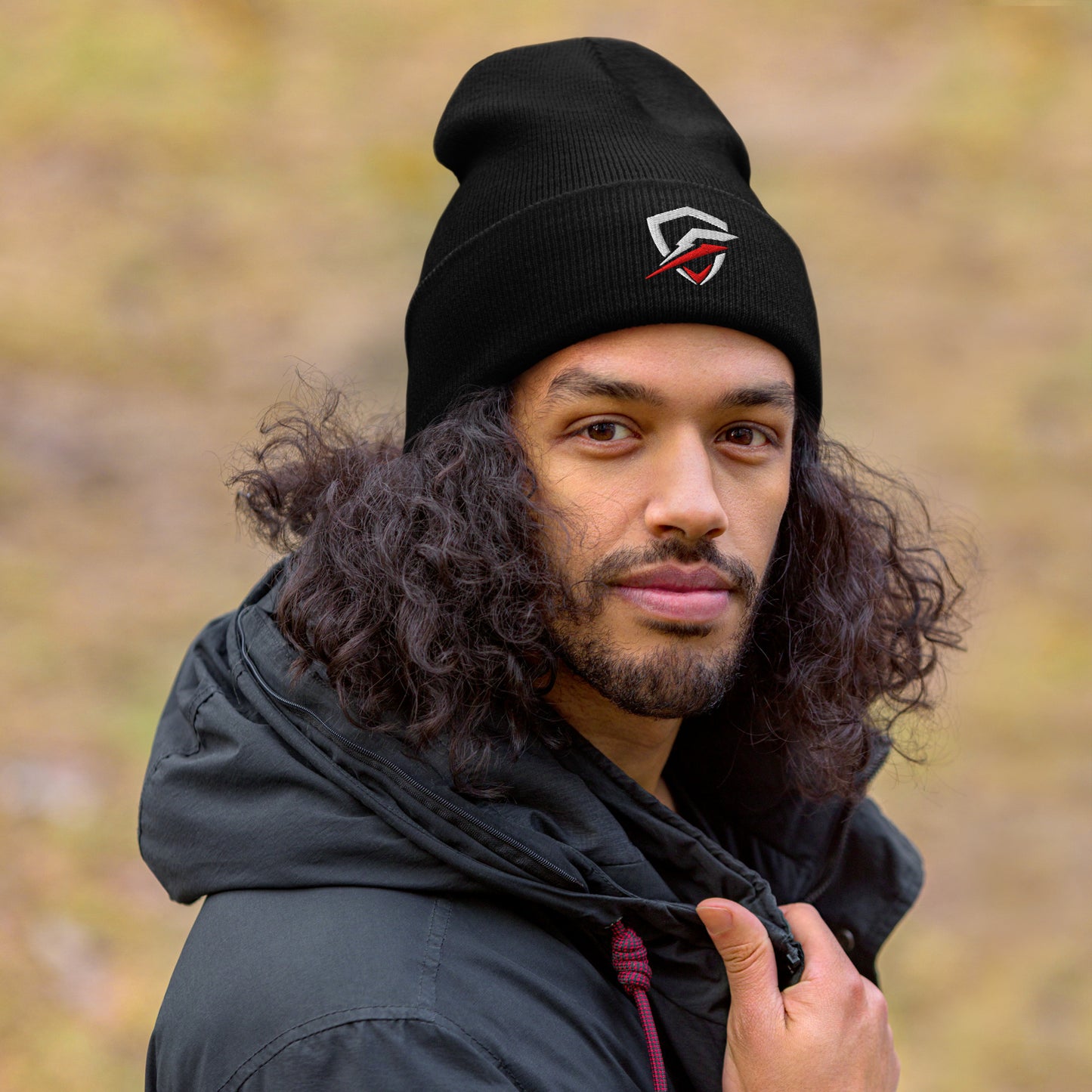 GT Beanie worn by a brown male with curly brown hair, wearing a black jacket and looking into the camera